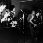 On bass guitar, a blue and white Vantage Flying V - High School 1985